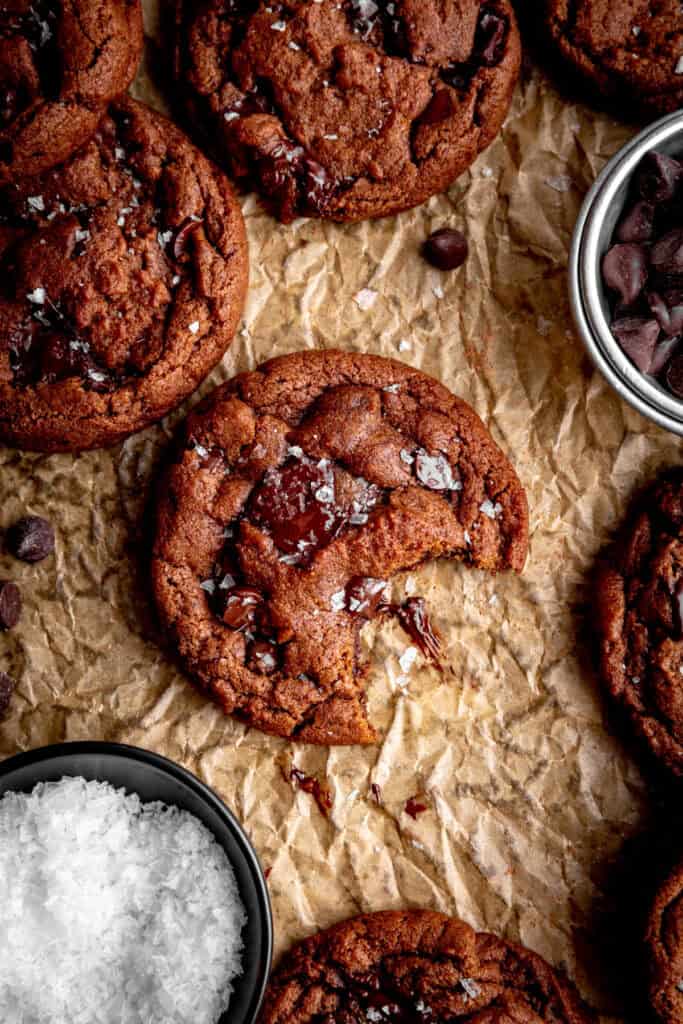 Double chocolate cookie with a bite taken out of it and a cup of flaky salt.