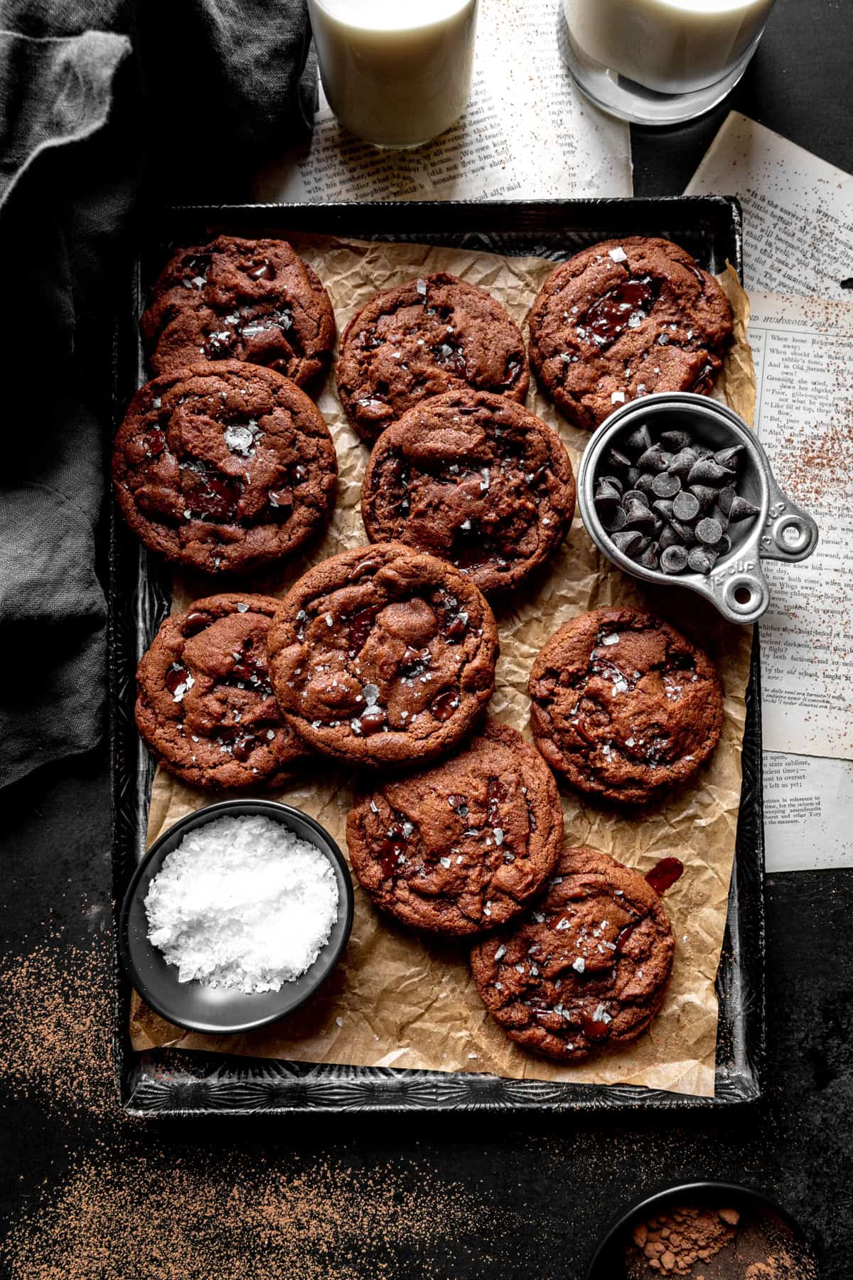 Double chocolate cookies on a baking sheet, a jug of milk and a linen napkin.