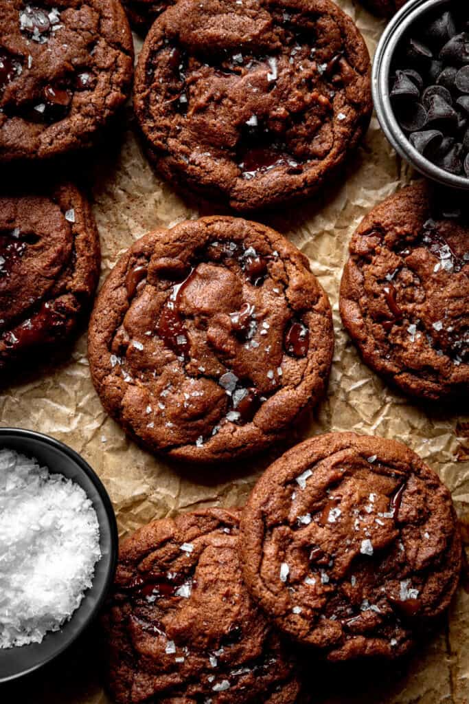 Double chocolate cookies, a bowl of flaky salt and a cup of chocolate chips.