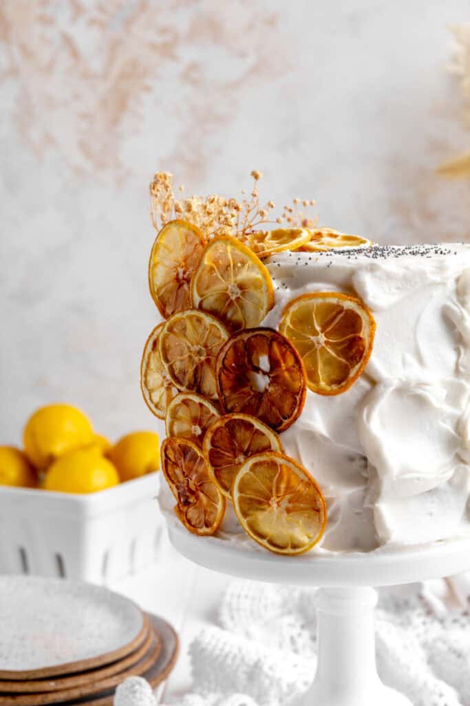 Dehydrated lemons on a lemon layer cake and a basket of lemons.