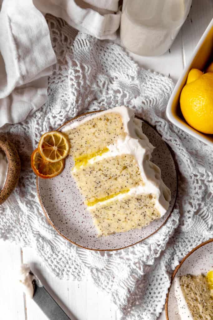 Slice of lemon poppyseed cake on a plate and a jug of milk.