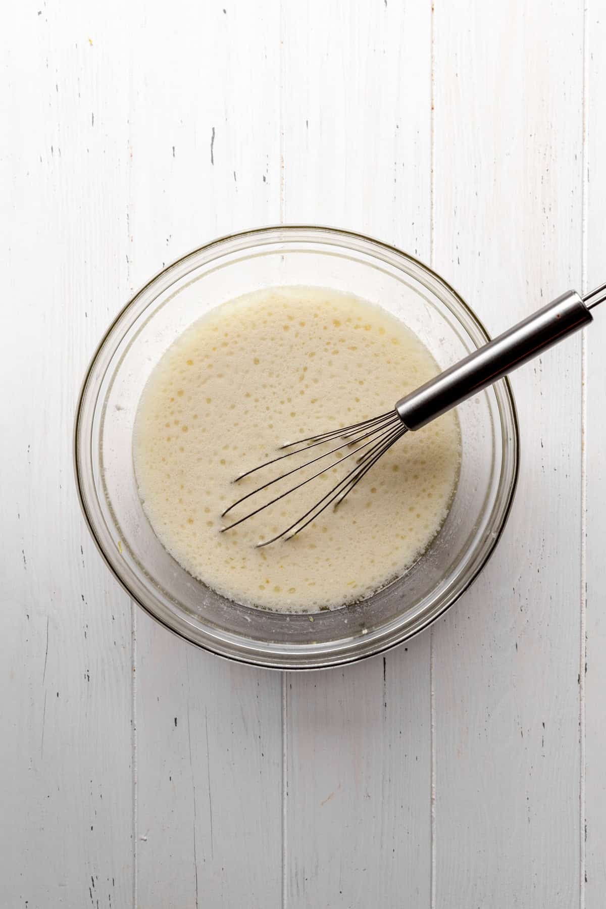 Nondairy milk, sugar and oil in a glass bowl with a wire whisk.