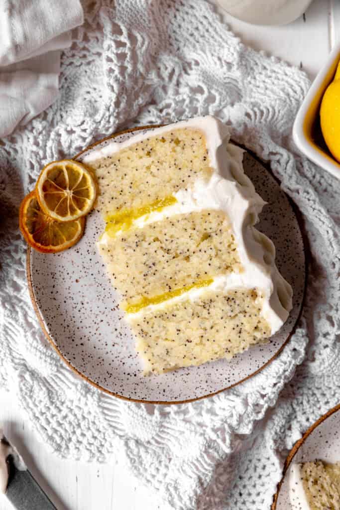 Slice of lemon poppyseed layer cake on a white plate.