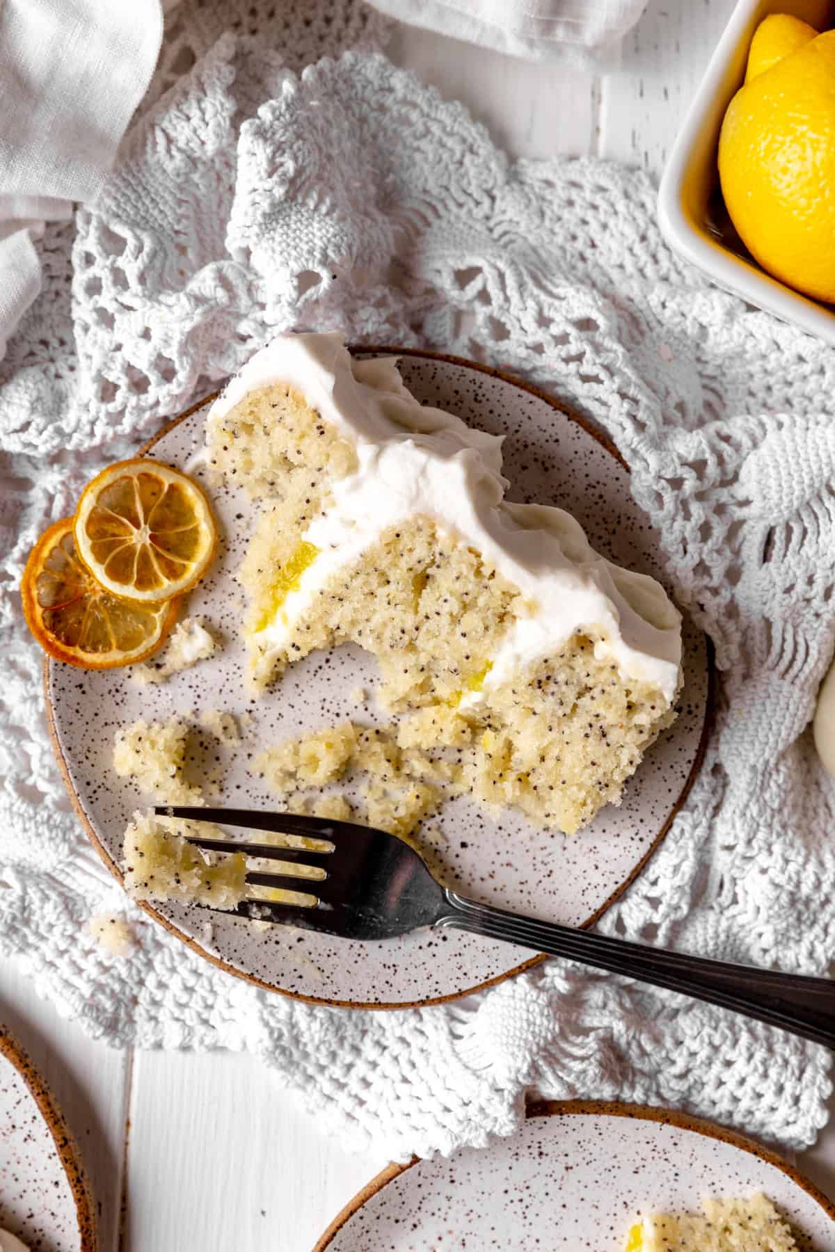 Half eaten slice of lemon poppyseed cake on a white plate.