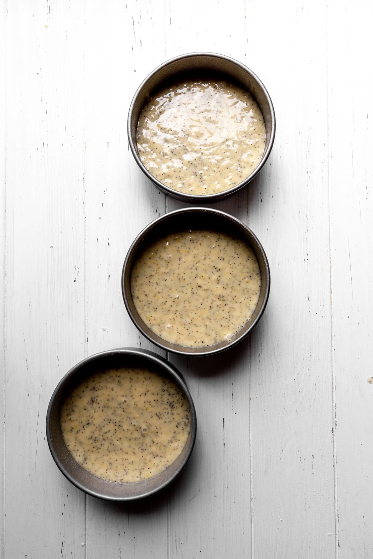 Cake pans filled with lemon poppyseed cake batter.