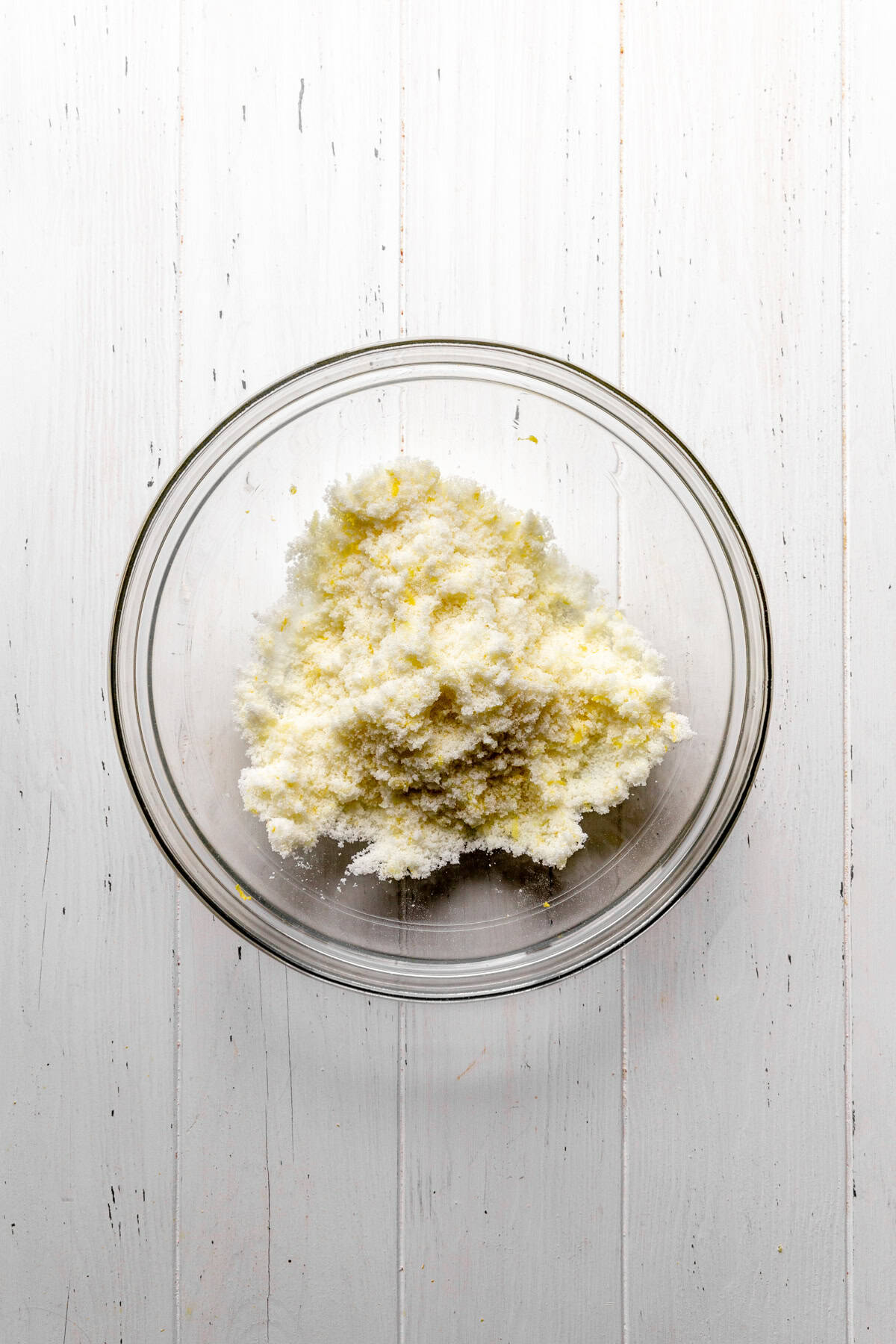 Sugar and lemon zest in a glass bowl.