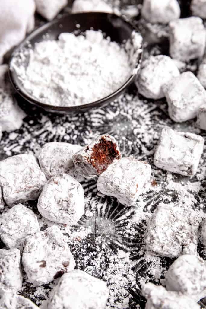 Brownie bite with a bite taken out of it and a cup of powdered sugar.