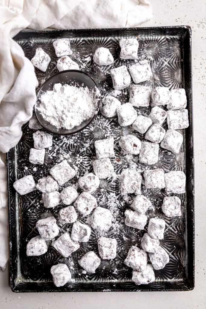 Brownie bites and a cup of powdered sugar on a baking sheet.