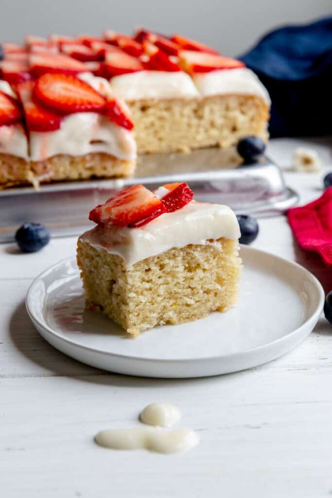 Slice of cake topped with strawberries on a white plate.