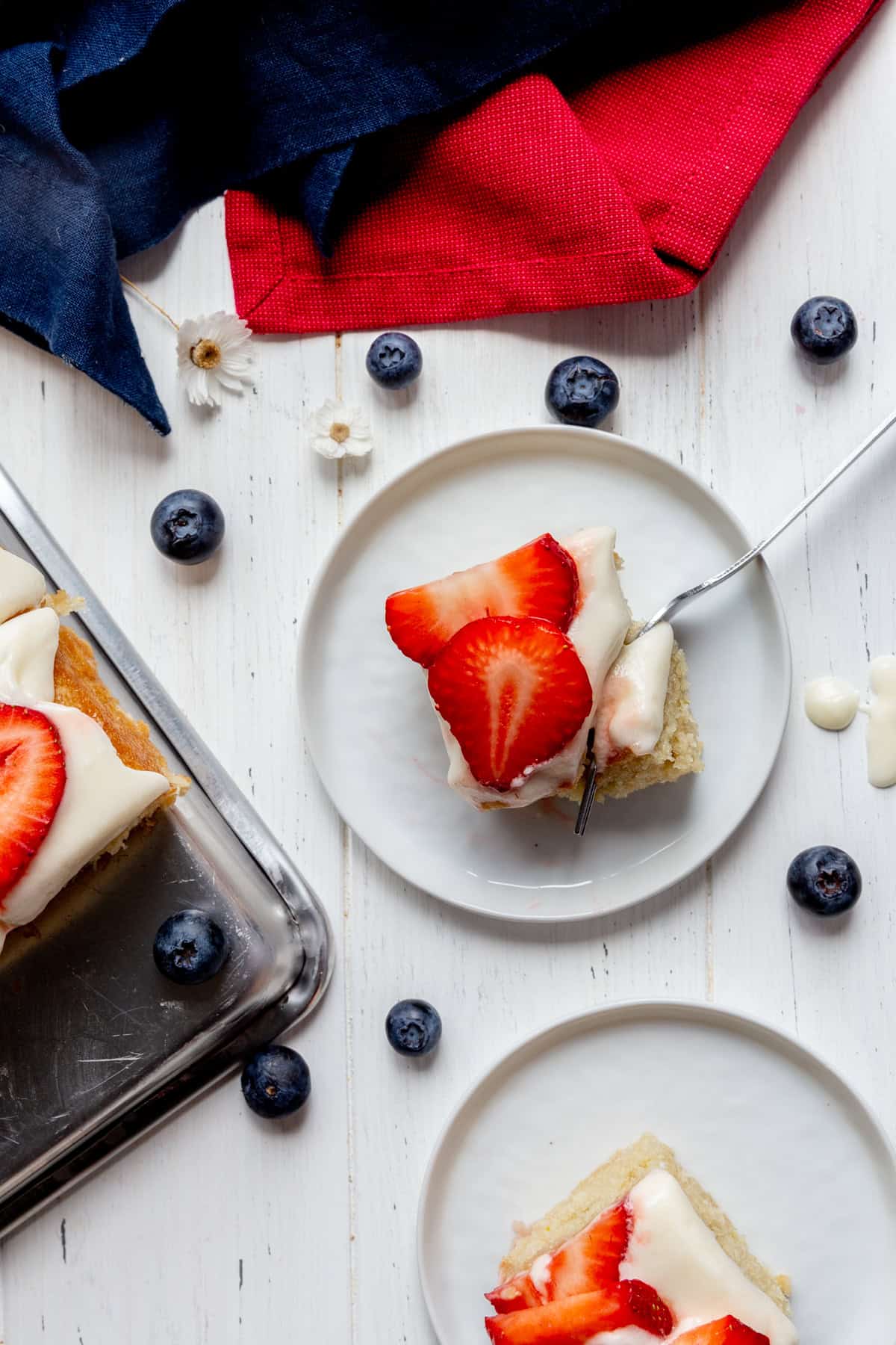 Fork cutting into a slice of flag cake and a red linen napkin.