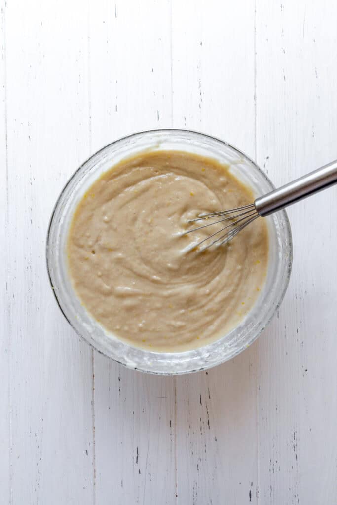 Glass bowl of cake batter with a whisk.