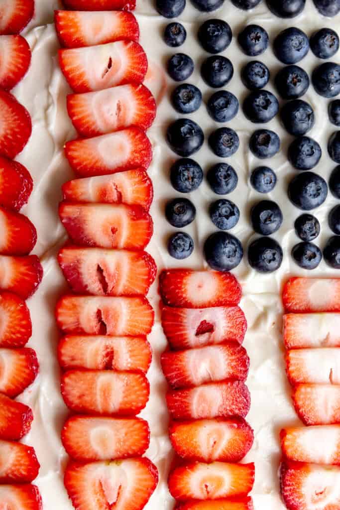 Blueberries and sliced strawberries laid out across frosting.