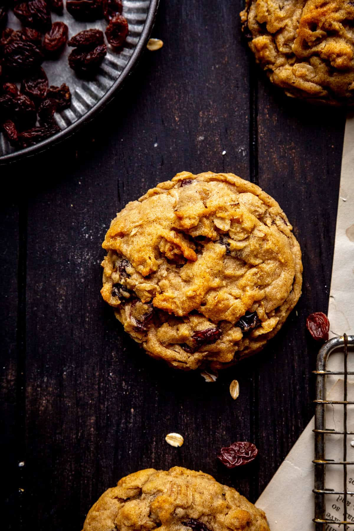 Oatmeal raisin cookie on dark wood surface.