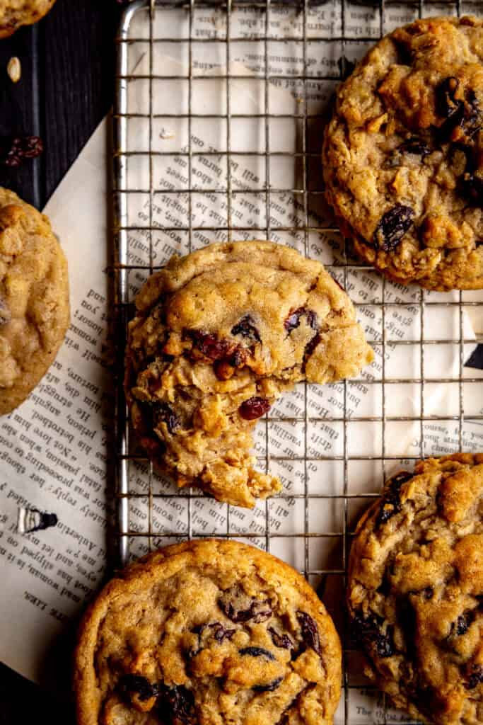 Oatmeal raisin cookie with a bite taken out of it sitting on book pages.