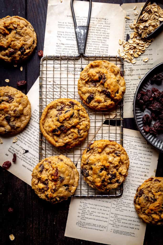 Oatmeal raisin cookies on a wire rack and a plate of raisins.