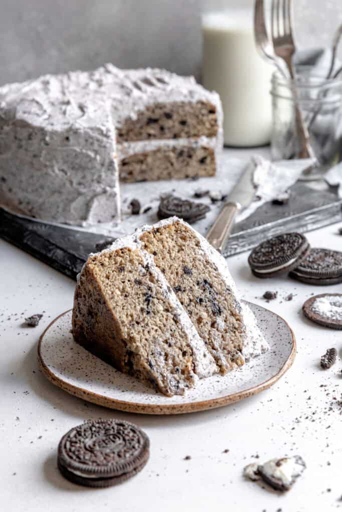 Whole oreo cake and a slice of oreo cake on a white plate.