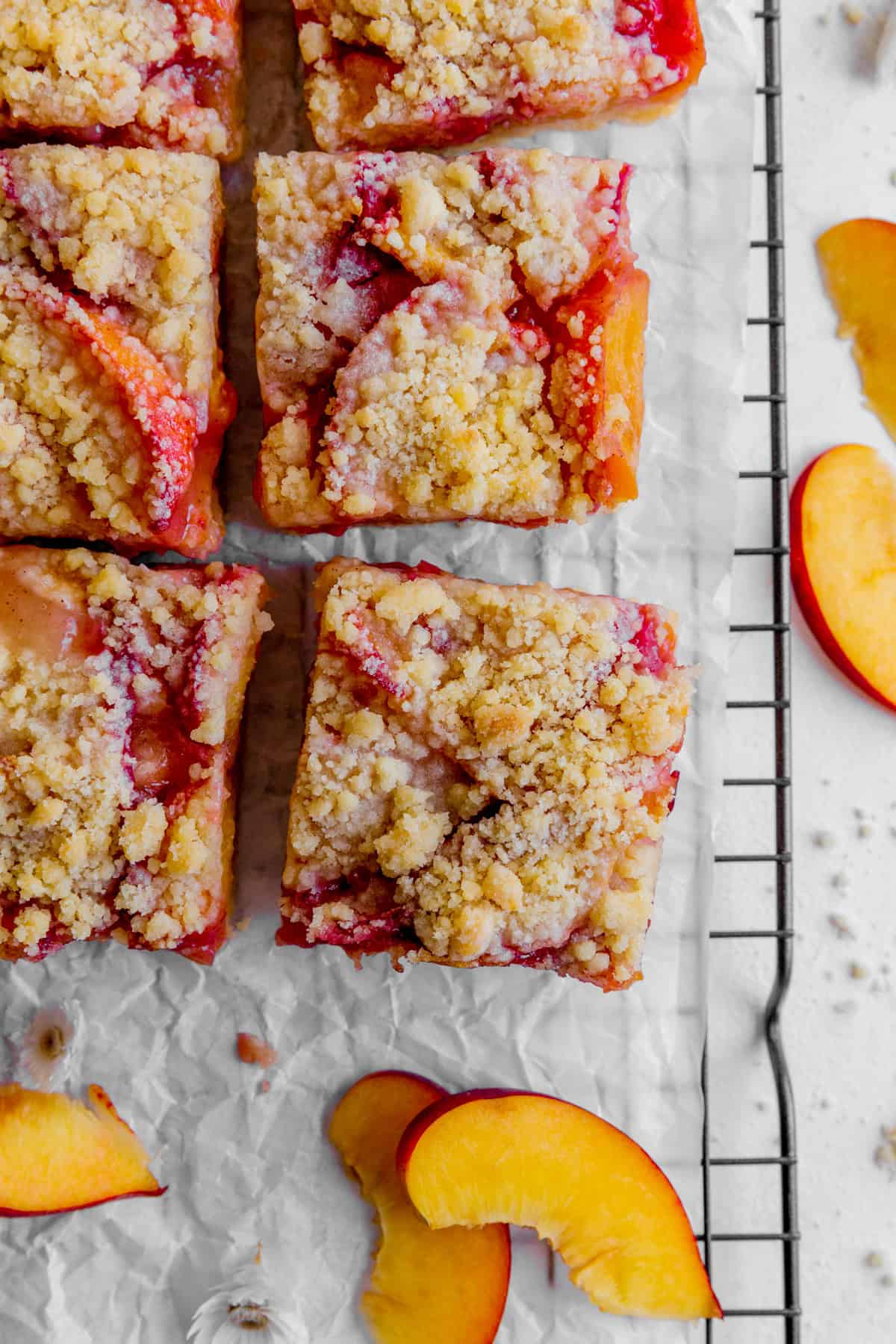 Peach crumble bars on a wire rack and peach slices.