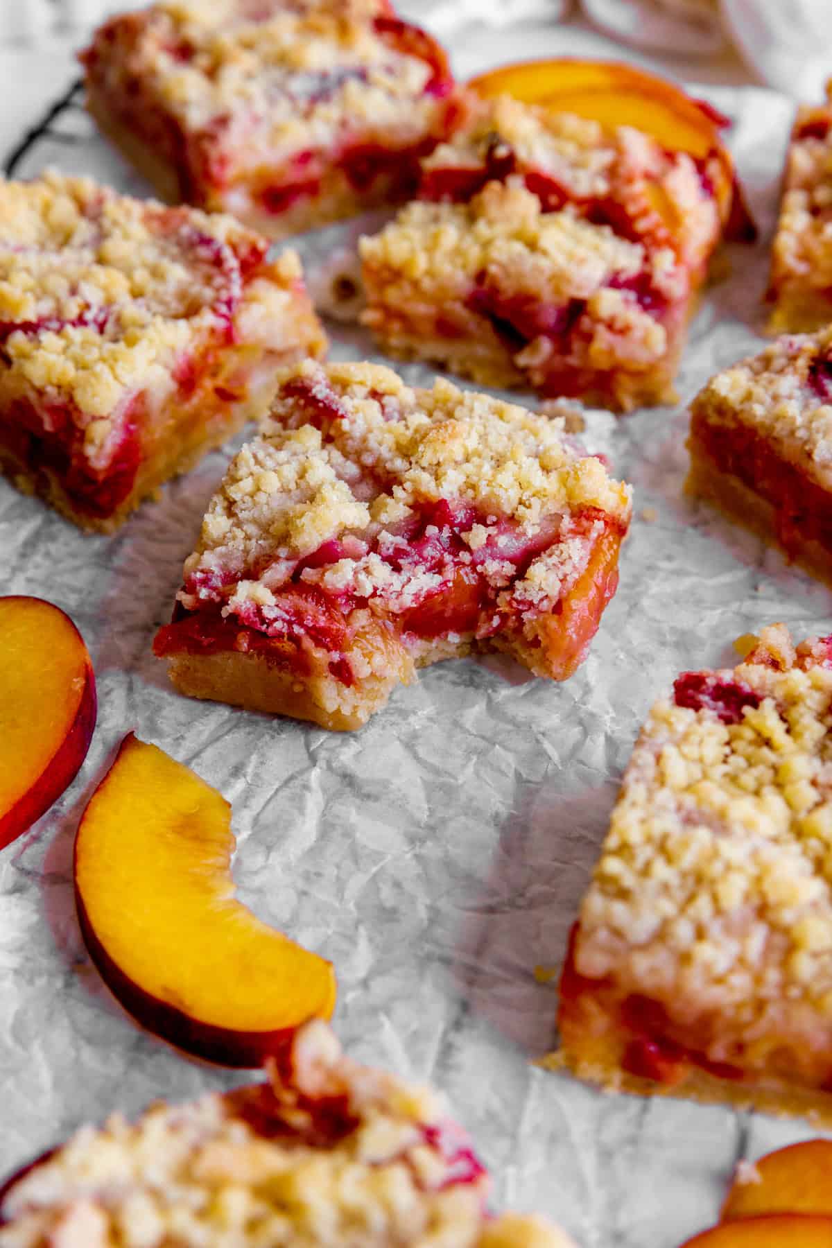 Peach crumble bar with a bite taken out of it surrounded by more bars.