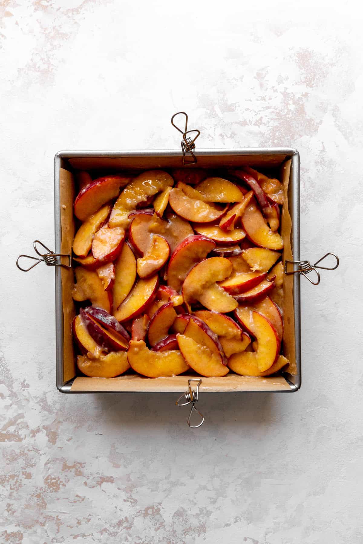 Peach slices laid out in a square pan.