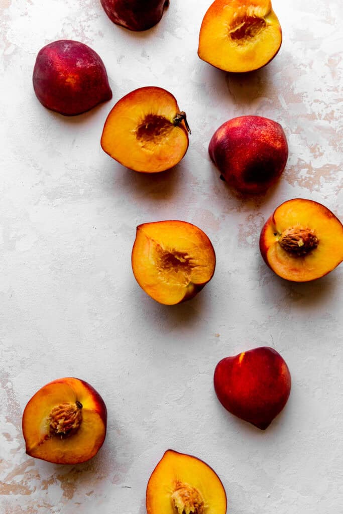 Peach halves spread out over a white surface.