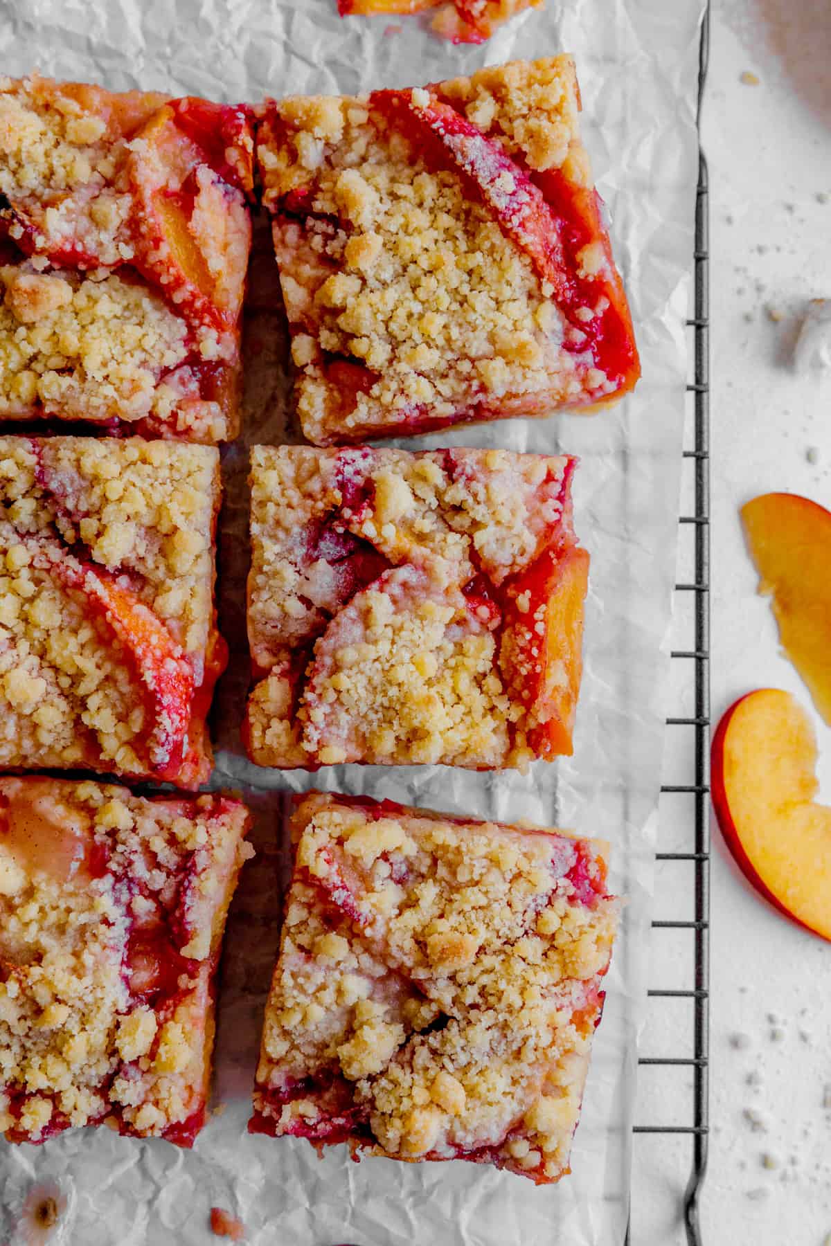 Peach crumble bars on parchment paper and peach slices.