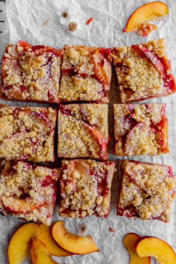 Peach crumble bars on a wire cooling rack and peach slices.
