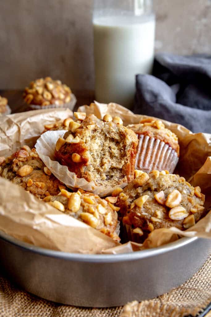 Peanut butter banana muffin with a bite taken out of it in a bowl with more muffins.