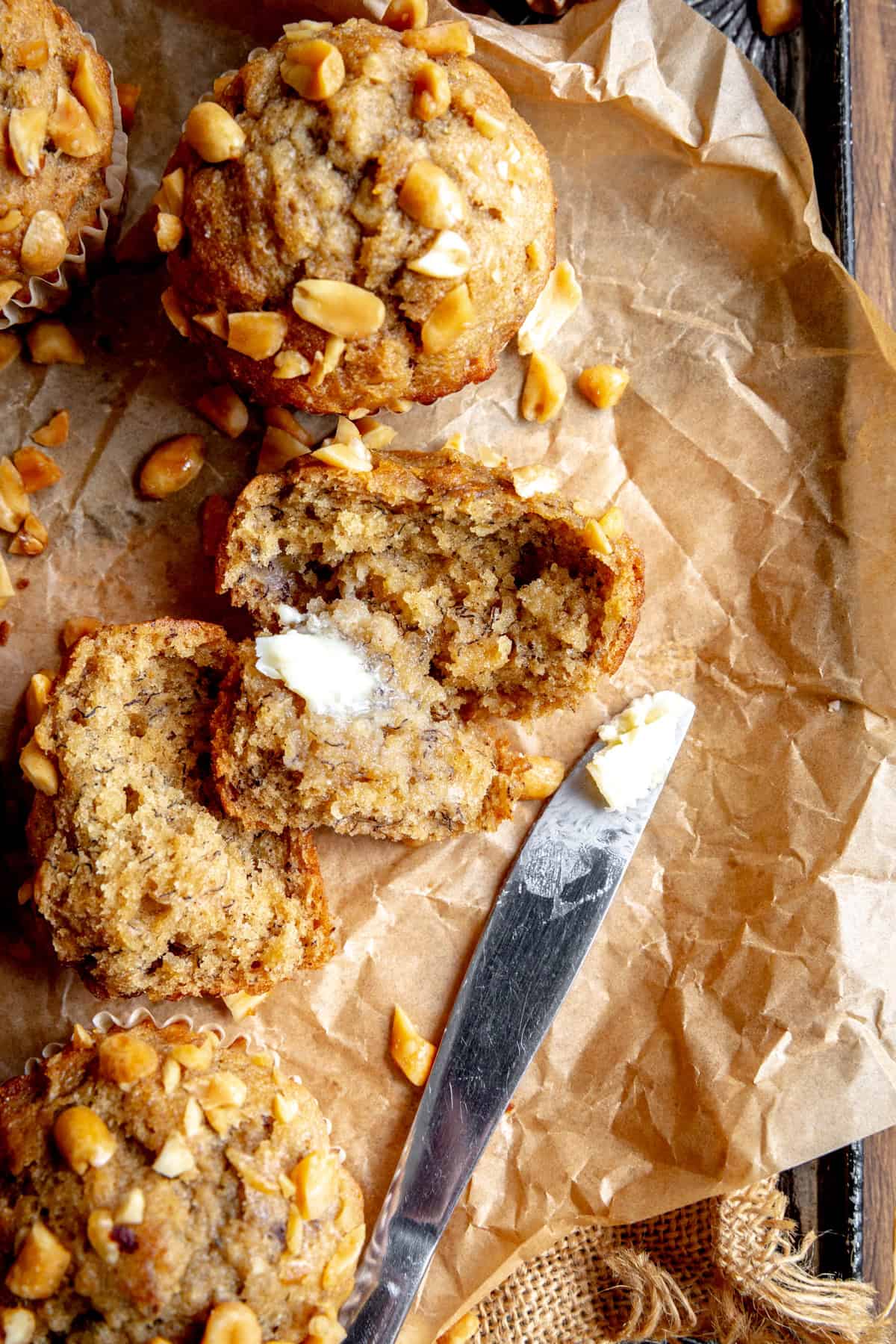 Peanut butter banana muffin cut in half and a knife covered in butter.