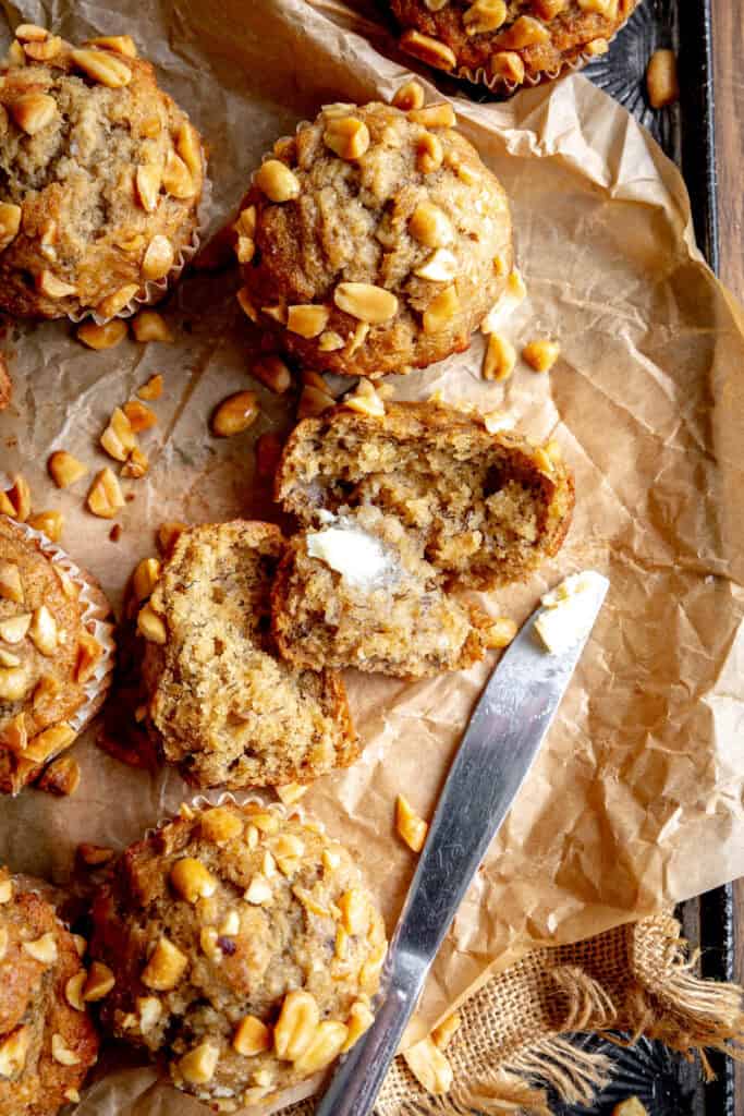 Peanut butter banana muffin cut in half and a knife covered in butter.