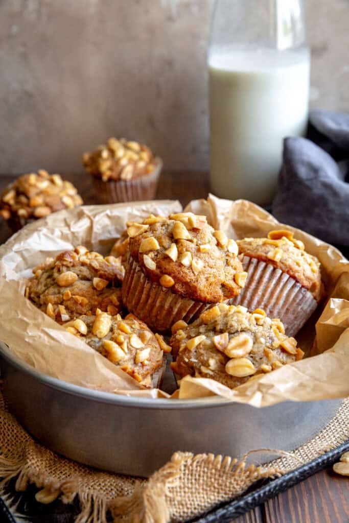 Peanut butter banana muffins in a round pan and a jug of milk.