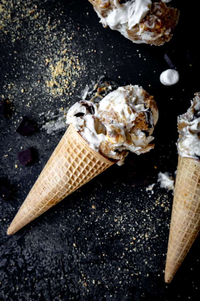 Sugar cone topped with lopsided scoops of s'mores ice cream.