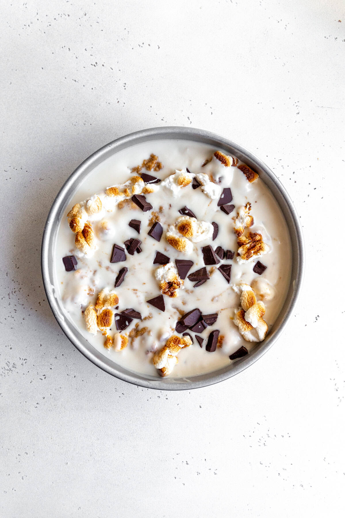 Unfrozen s'mores ice cream in a round cake pan.