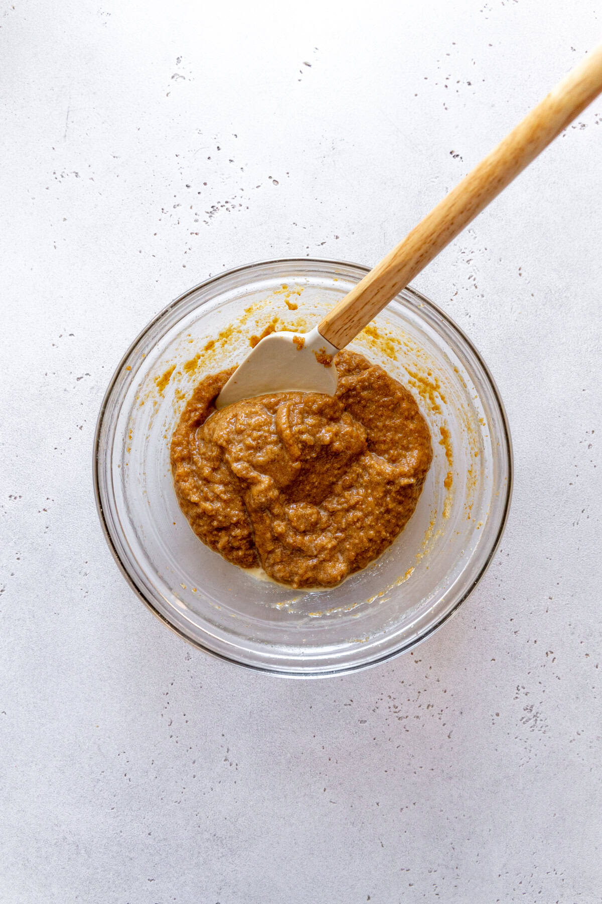 Glass bowl of graham cracker swirl with a rubber spatula.
