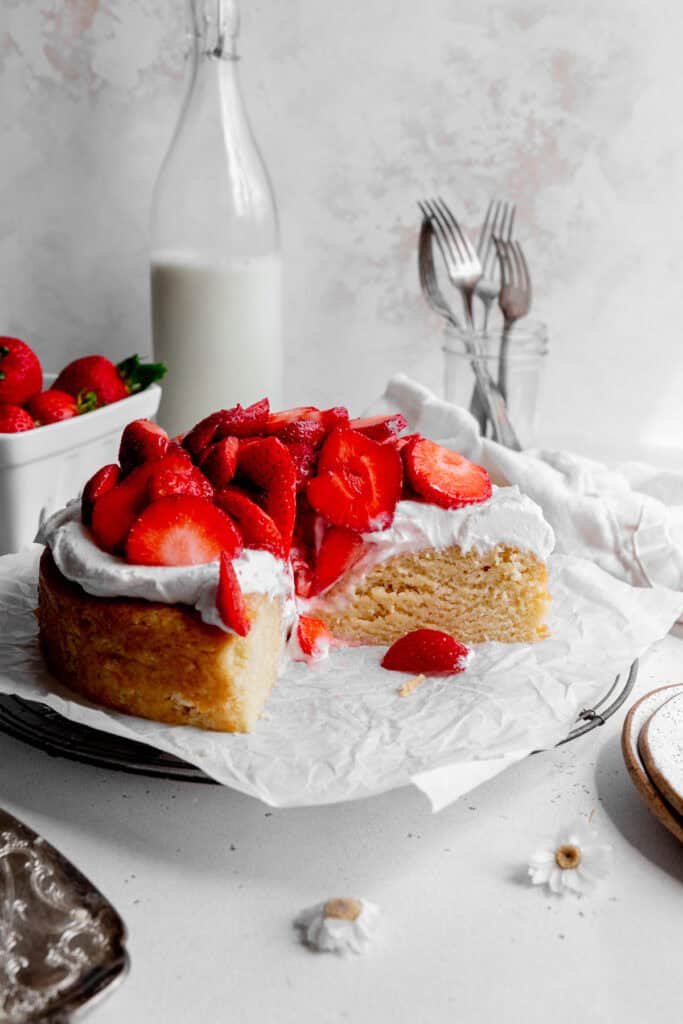 Shortcake topped with whipped cream and strawberries with slices missing.