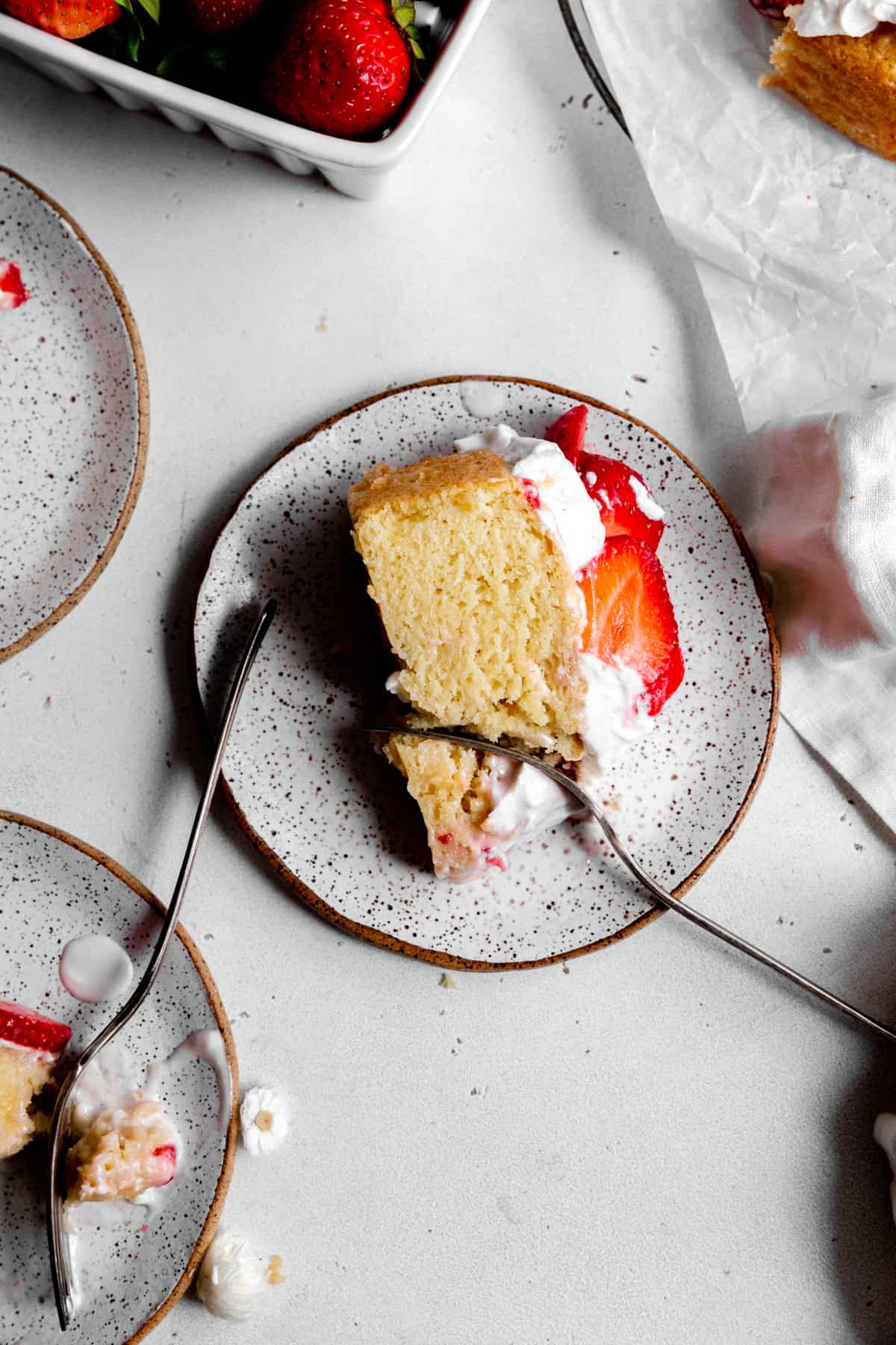 Fork cutting into a slice of strawberry shortcake cake.