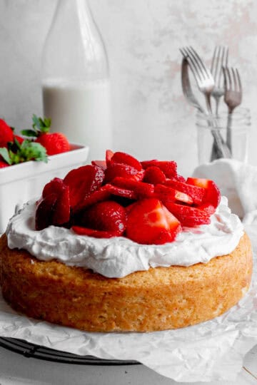 Strawberry shortcake cake, a jug of milk and a basket of strawberries.