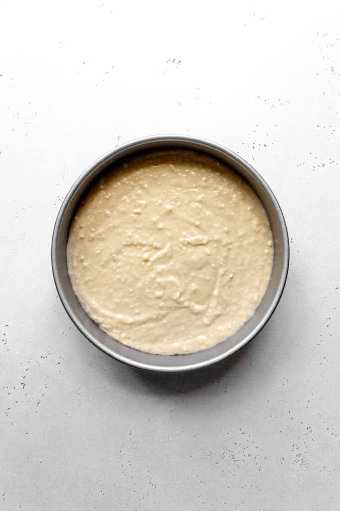 Unbaked shortcake in a round cake pan.
