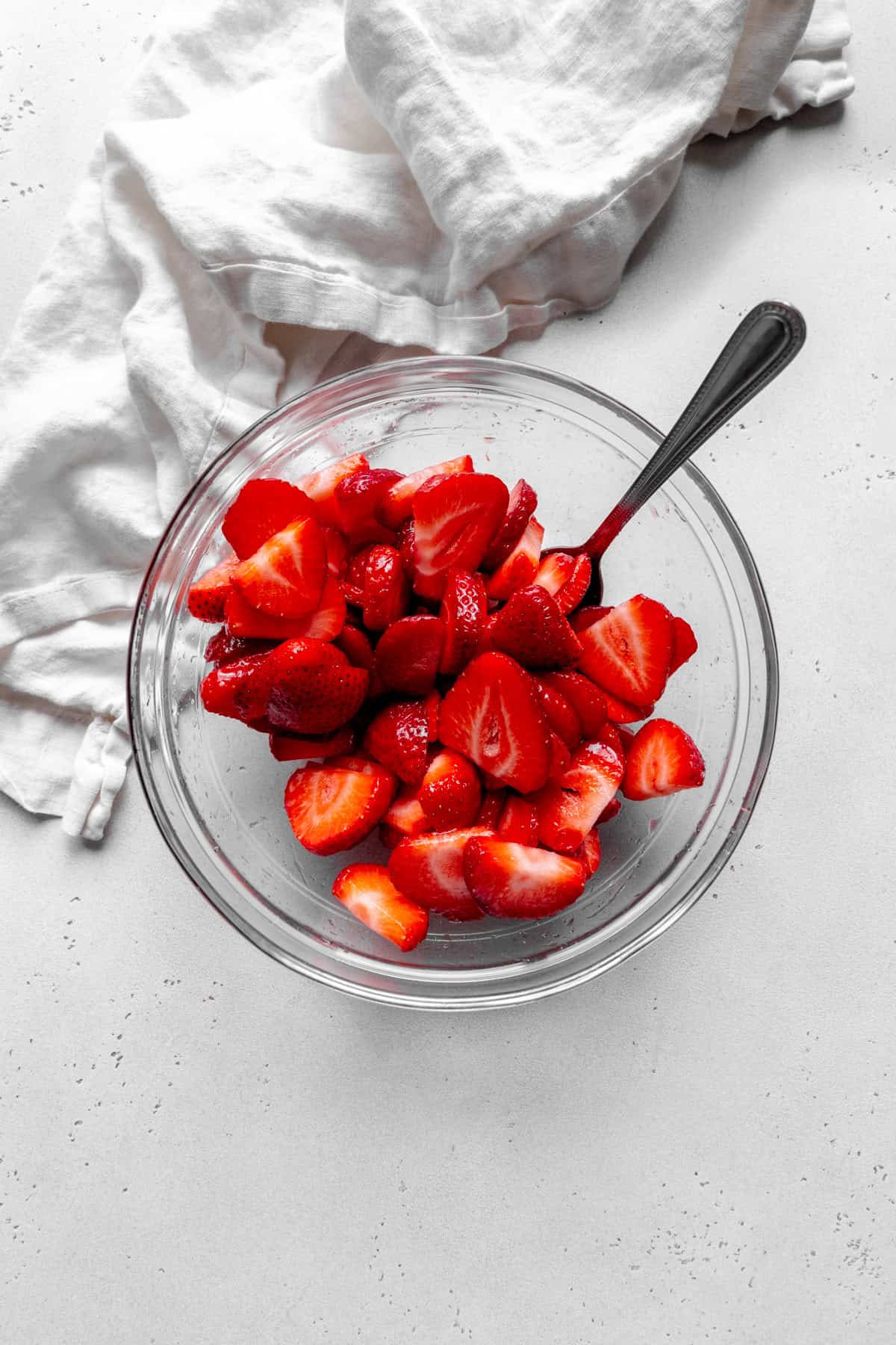 Glass bowl of sliced strawberries.