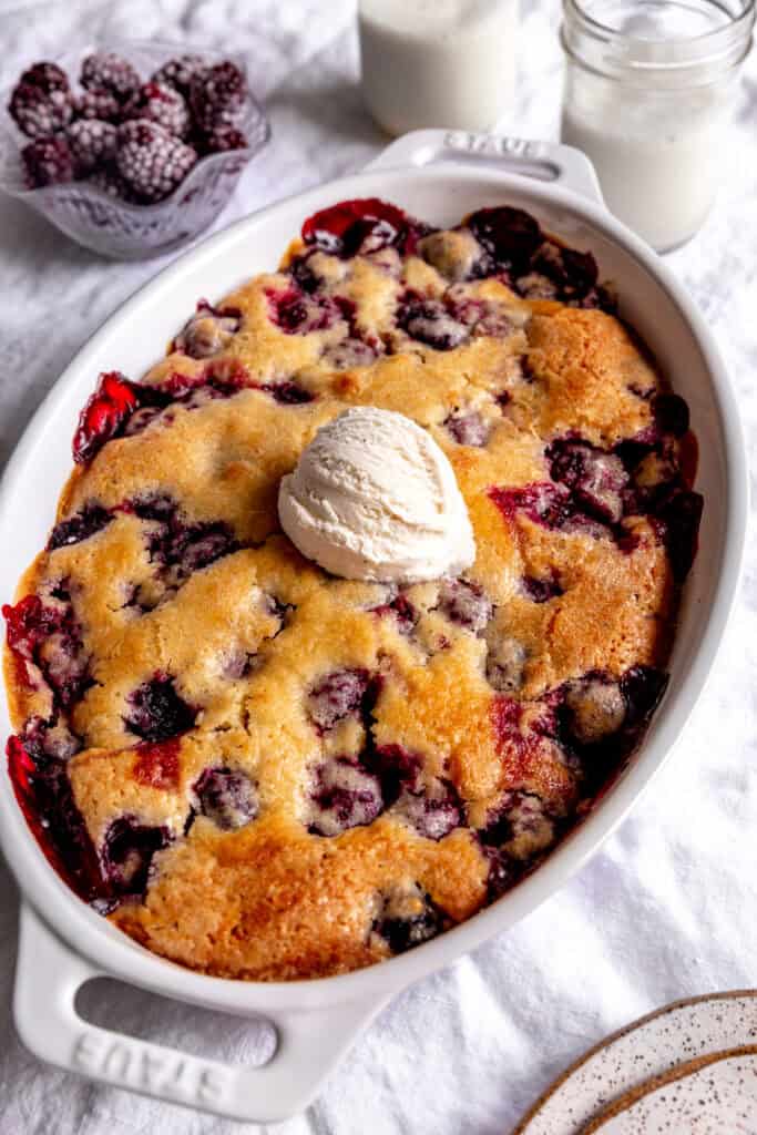 Blackberry cobbler topped with vanilla ice cream and a glass of milk.