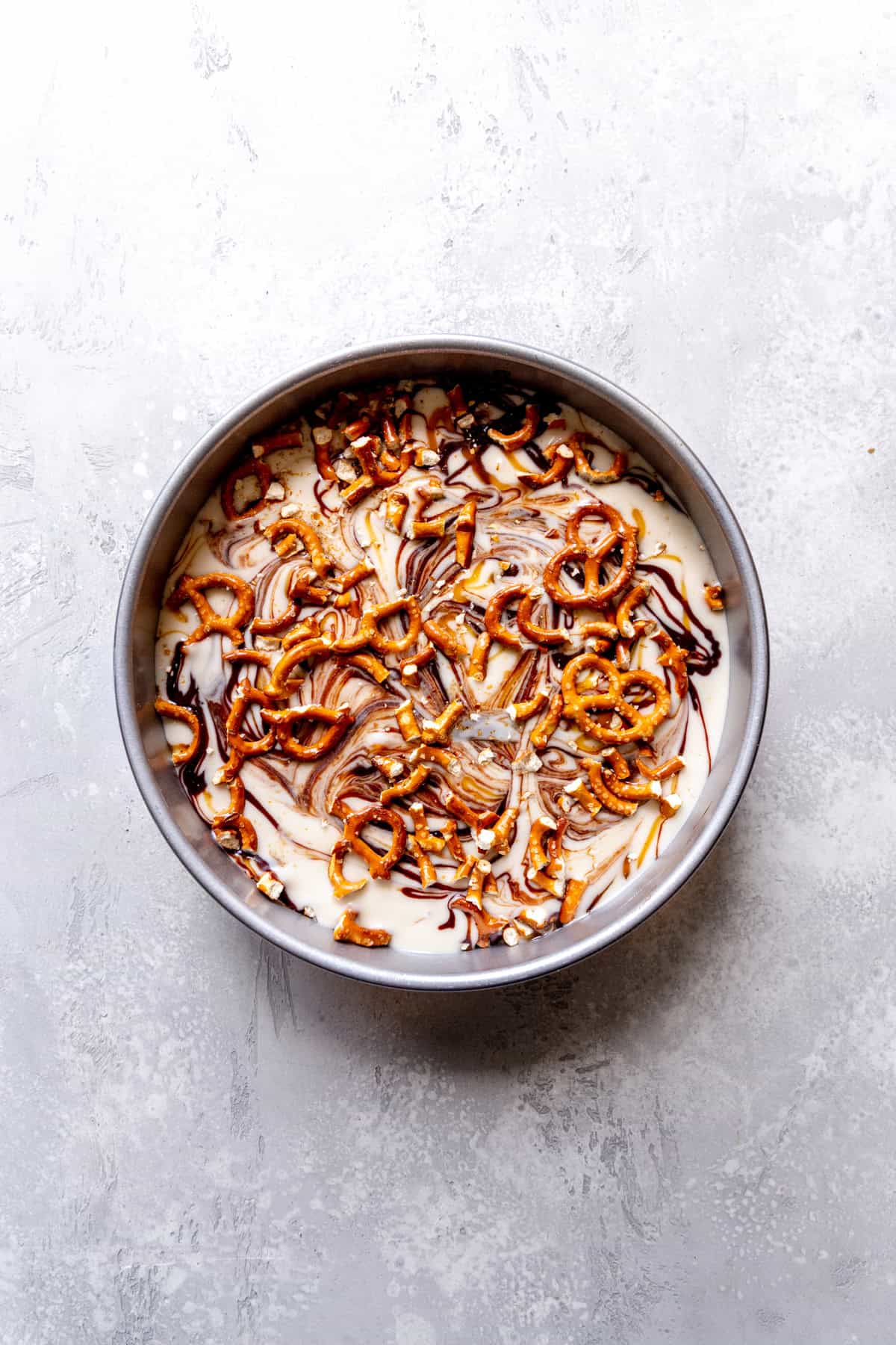 Unfrozen caramel pretzel ice cream in a round cake pan.
