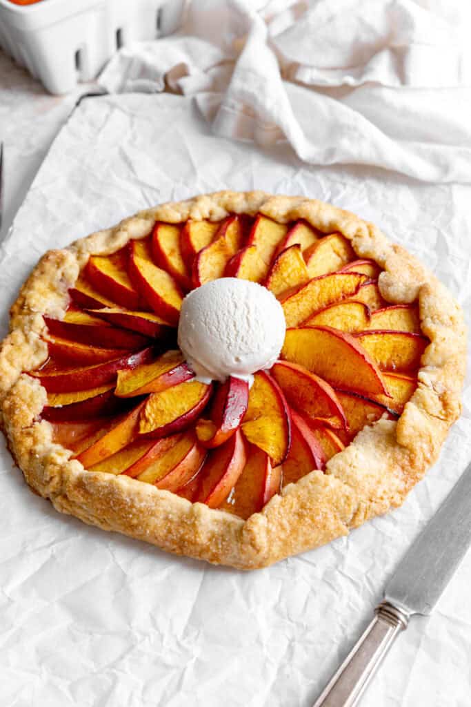 Nectarine galette, a knife and a linen napkin.