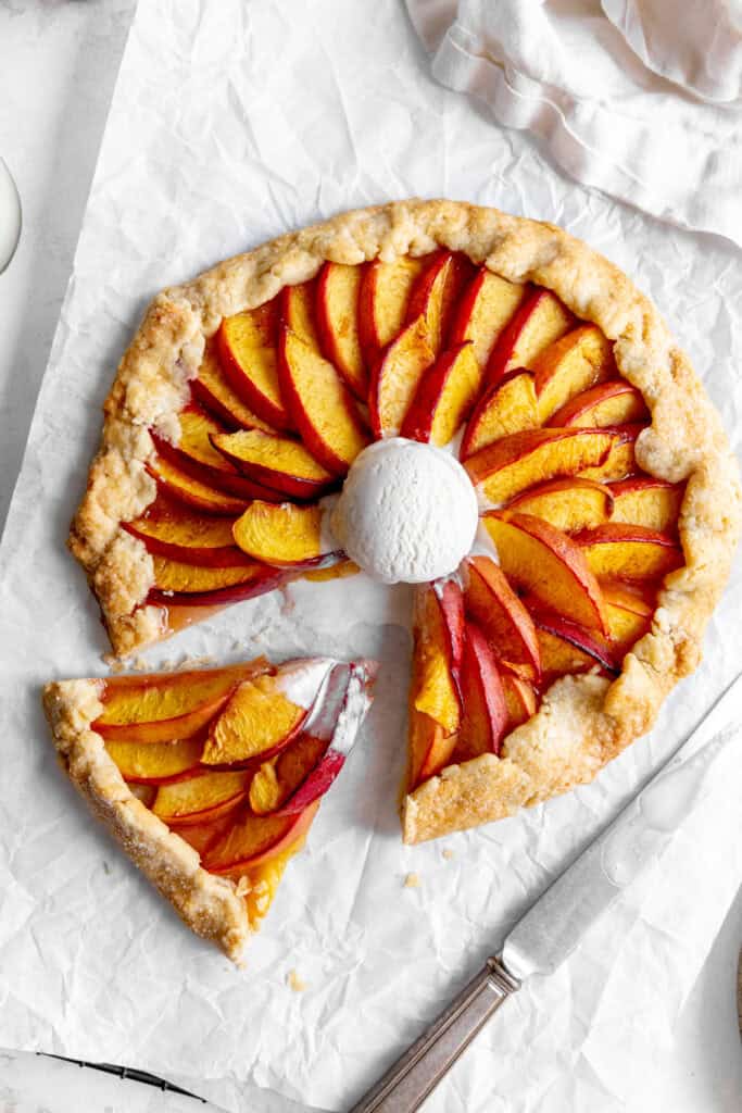 Sliced nectarine galette topped with a scoop of vanilla ice cream.