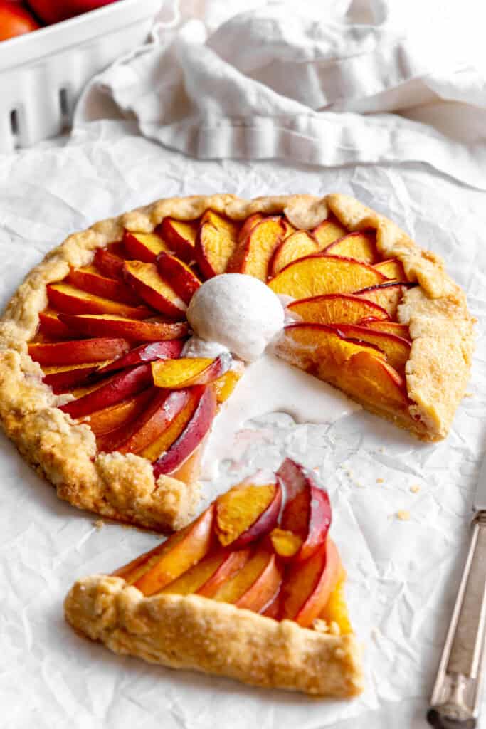 Sliced nectarine galette topped with melted vanilla ice cream and a basket of nectarines.