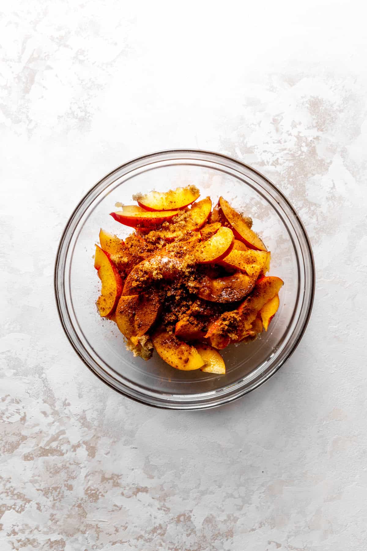 Sliced nectarines in a bowl with sugar and cinnamon.