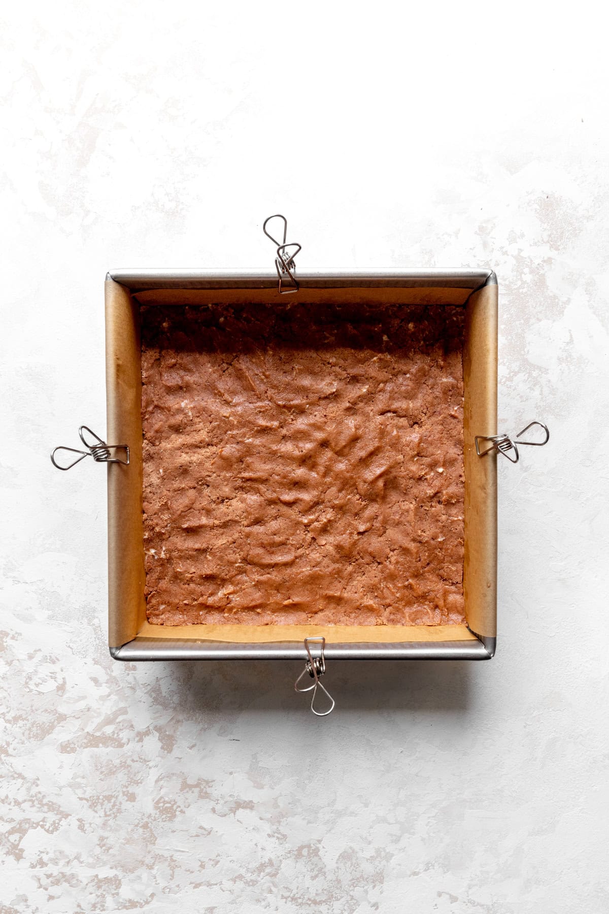 Unbaked chocolate shortbread crust pressed into a square pan.