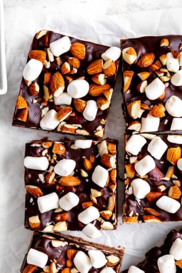 Rocky road bars on white parchment paper and a cup of chocolate chips.