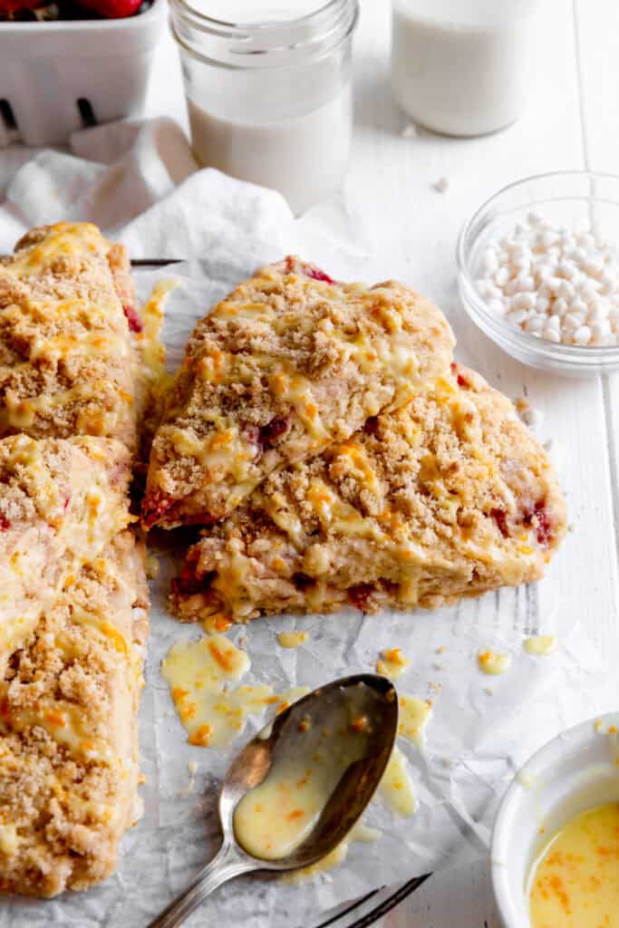 Strawberry rhubarb scones, a glass of milk and a bowl of orange glaze.