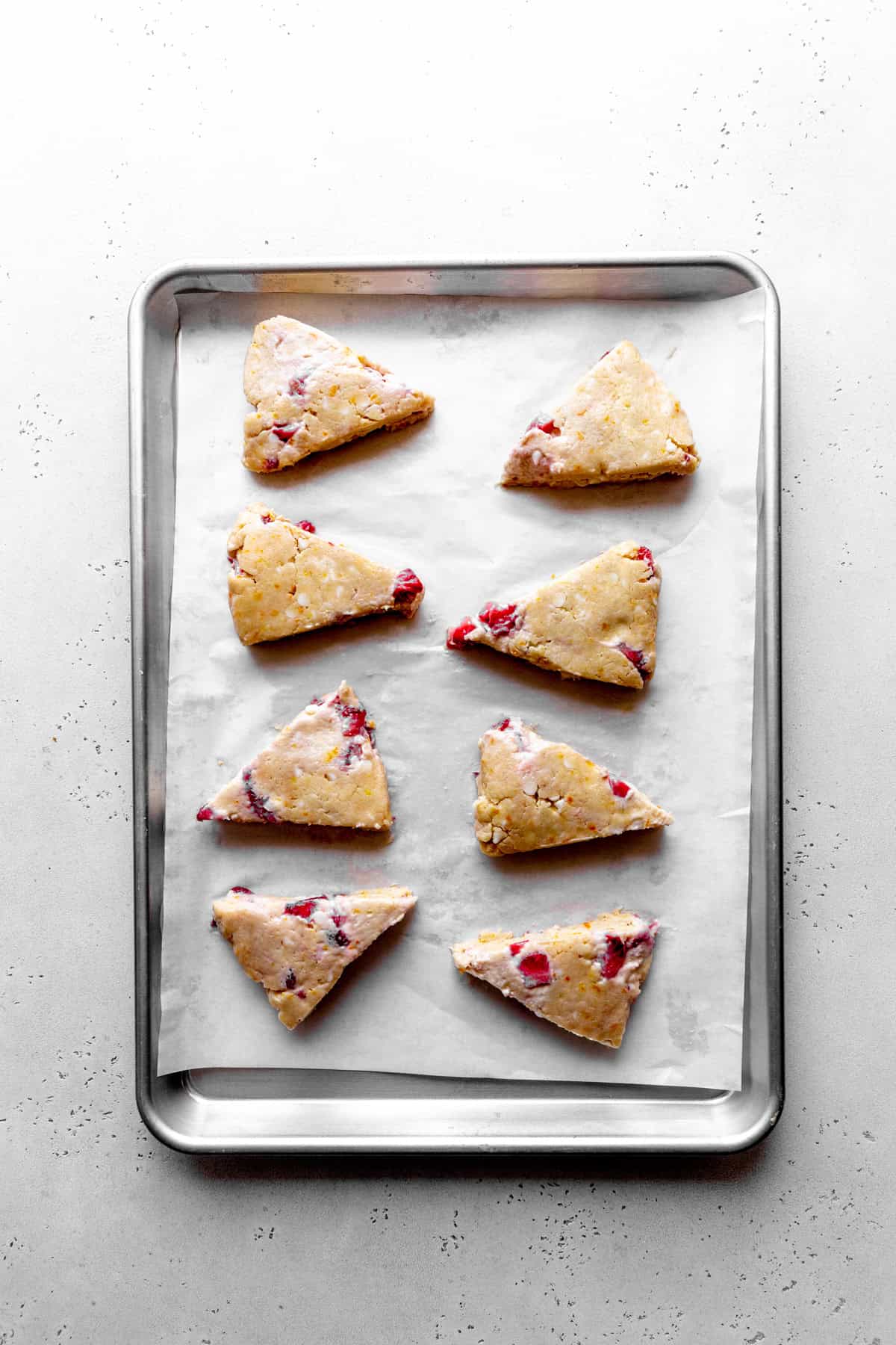 Unbaked strawberry rhubarb scones on a baking sheet.
