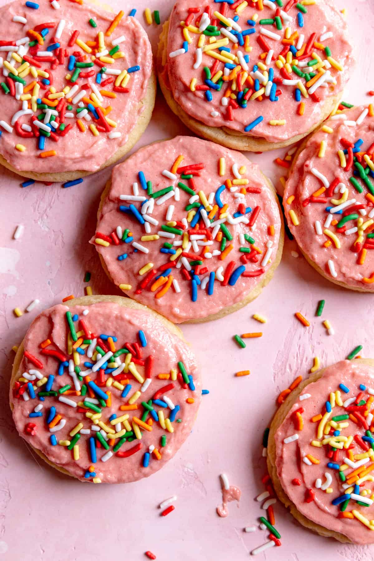 Sugar cookies topped with pink frosting and sprinkles.