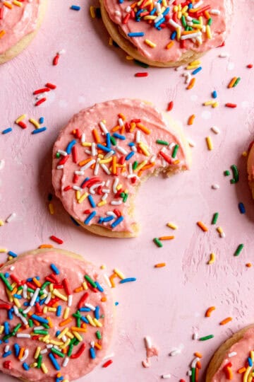 Sugar cookies spread out on a pink background.
